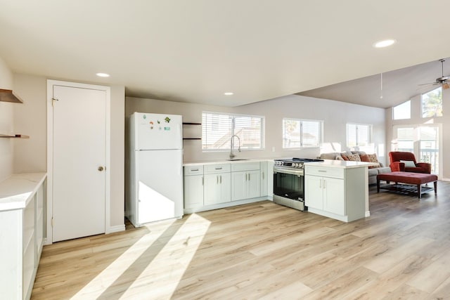 kitchen featuring white refrigerator, ceiling fan, light wood-type flooring, stainless steel range, and kitchen peninsula