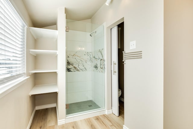 bathroom with toilet, an enclosed shower, and hardwood / wood-style flooring