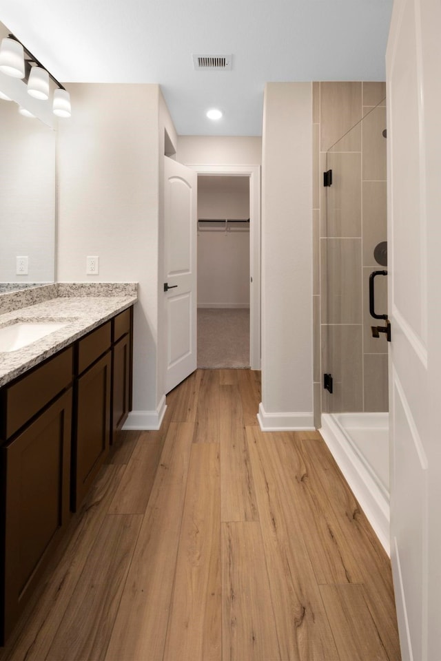 bathroom featuring hardwood / wood-style floors, vanity, and a shower with door