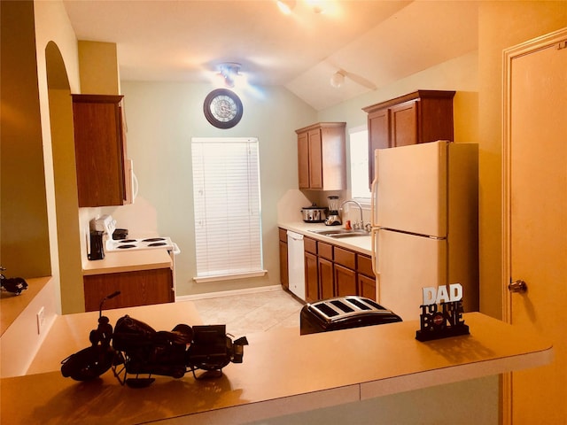 kitchen featuring white appliances, lofted ceiling, and sink