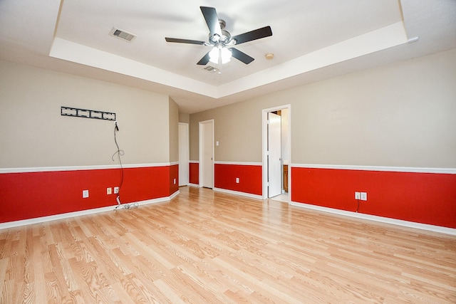 spare room featuring ceiling fan, a raised ceiling, and light hardwood / wood-style floors