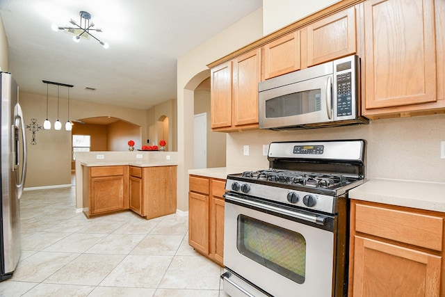 kitchen featuring light tile patterned flooring, appliances with stainless steel finishes, decorative light fixtures, and kitchen peninsula