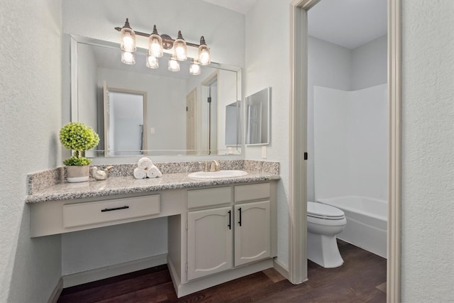 full bathroom with hardwood / wood-style floors, vanity, bathing tub / shower combination, and toilet