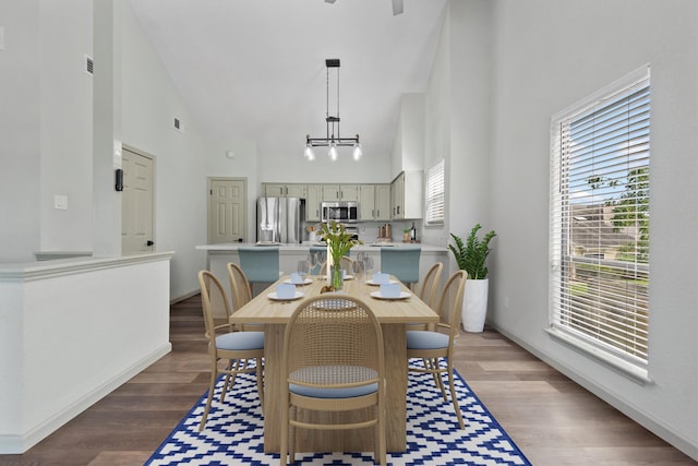 dining area with a chandelier, high vaulted ceiling, and wood-type flooring