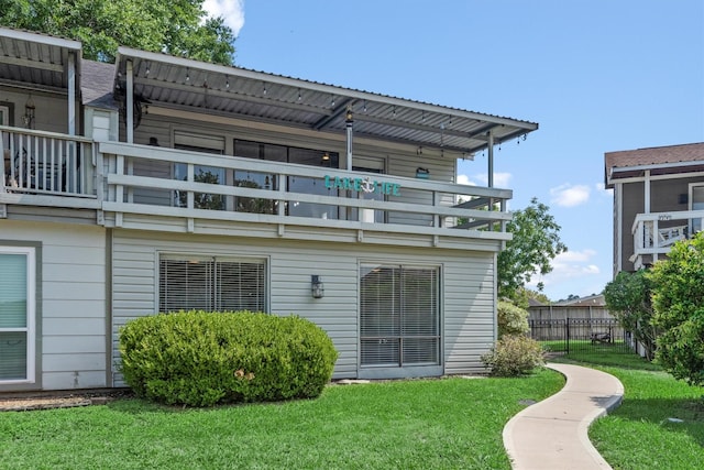 rear view of house with a balcony and a lawn