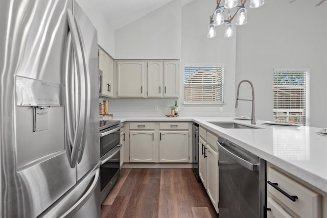 kitchen with appliances with stainless steel finishes, dark hardwood / wood-style flooring, sink, pendant lighting, and high vaulted ceiling