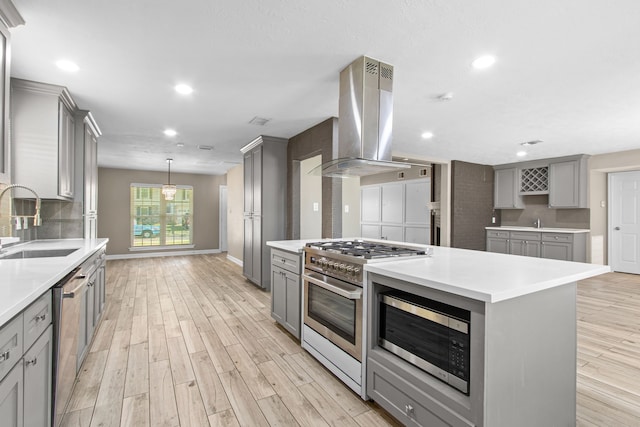 kitchen featuring island exhaust hood, stainless steel appliances, sink, a center island, and gray cabinets