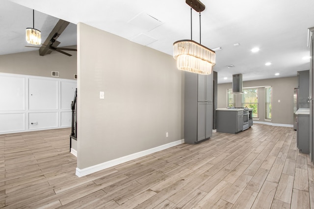 kitchen featuring vaulted ceiling with beams, island exhaust hood, gray cabinets, ceiling fan with notable chandelier, and light wood-type flooring