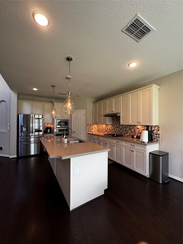 kitchen featuring sink, hanging light fixtures, decorative backsplash, a center island with sink, and appliances with stainless steel finishes