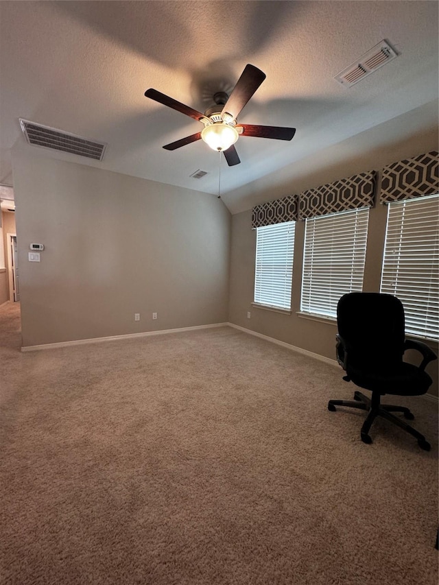 unfurnished office with carpet flooring, ceiling fan, a textured ceiling, and vaulted ceiling