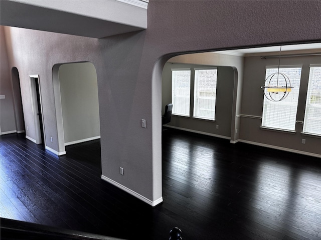 unfurnished room featuring dark wood-type flooring, a chandelier, and ornamental molding