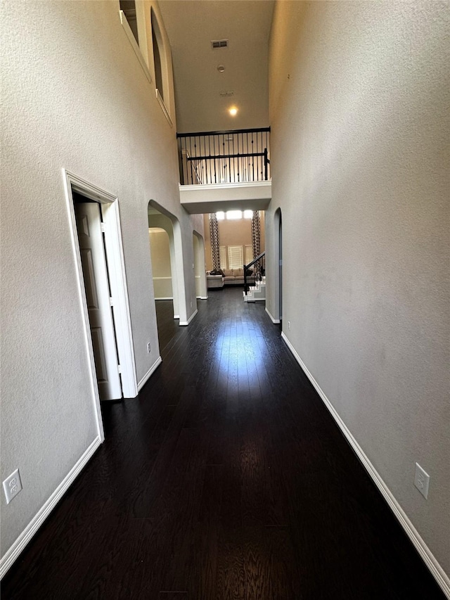 hallway featuring dark hardwood / wood-style floors and a towering ceiling