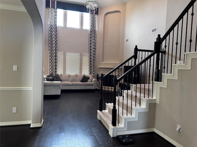 entrance foyer with dark hardwood / wood-style floors, crown molding, and a notable chandelier