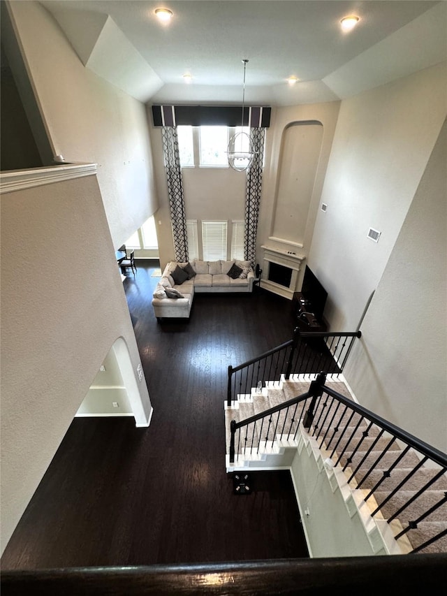 staircase featuring wood-type flooring, an inviting chandelier, and lofted ceiling