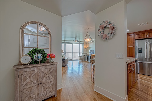 hall featuring visible vents, light wood-style flooring, and baseboards