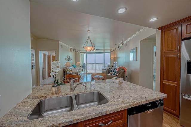 kitchen with appliances with stainless steel finishes, a sink, light stone counters, and crown molding