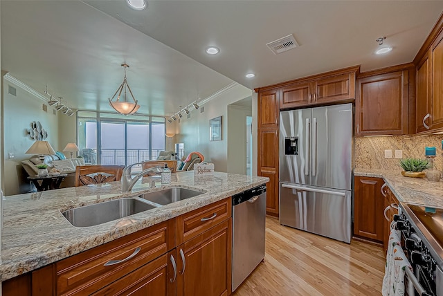 kitchen featuring visible vents, brown cabinetry, appliances with stainless steel finishes, light stone countertops, and a sink