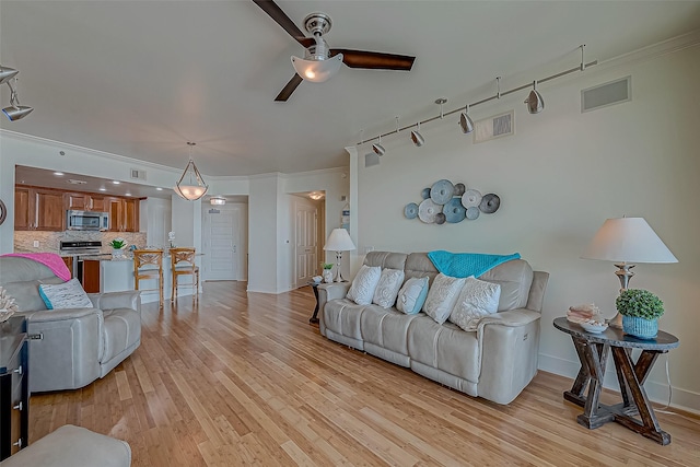 living area with ceiling fan, light wood finished floors, visible vents, and crown molding