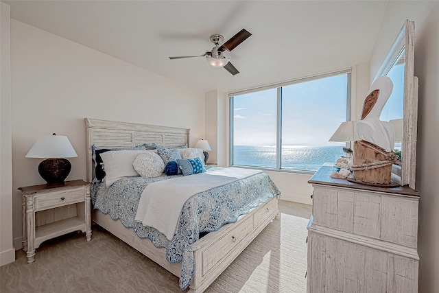 bedroom with a ceiling fan, light carpet, a water view, and baseboards