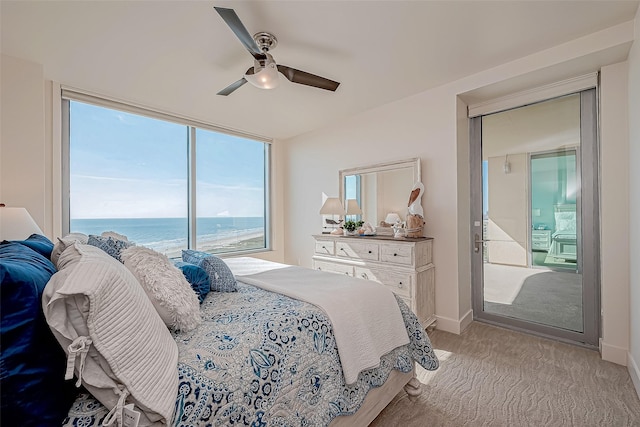 bedroom featuring light colored carpet, ceiling fan, baseboards, and a water view