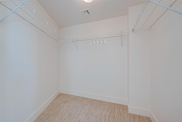 walk in closet with light colored carpet and visible vents