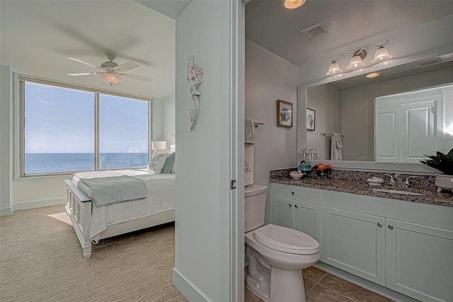 bathroom with ceiling fan, toilet, vanity, visible vents, and ensuite bath