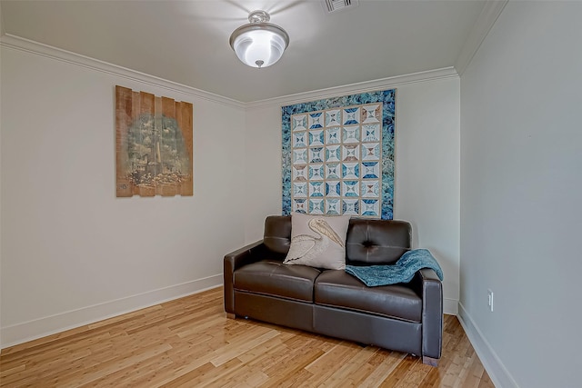 sitting room with ornamental molding, visible vents, light wood-style flooring, and baseboards