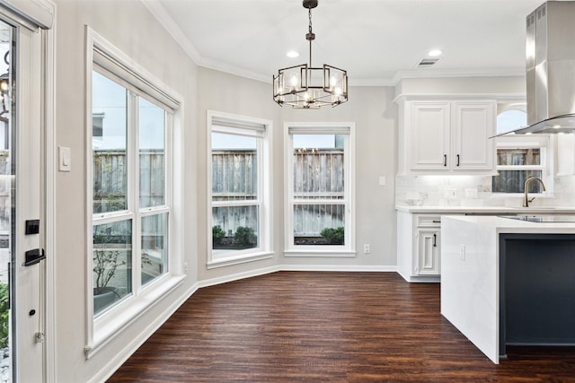 kitchen featuring dark hardwood / wood-style flooring, tasteful backsplash, wall chimney range hood, an inviting chandelier, and white cabinets