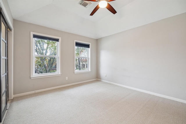 spare room with ceiling fan, light colored carpet, and a tray ceiling