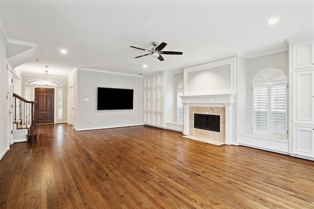 unfurnished living room with a tiled fireplace, crown molding, hardwood / wood-style floors, and ceiling fan