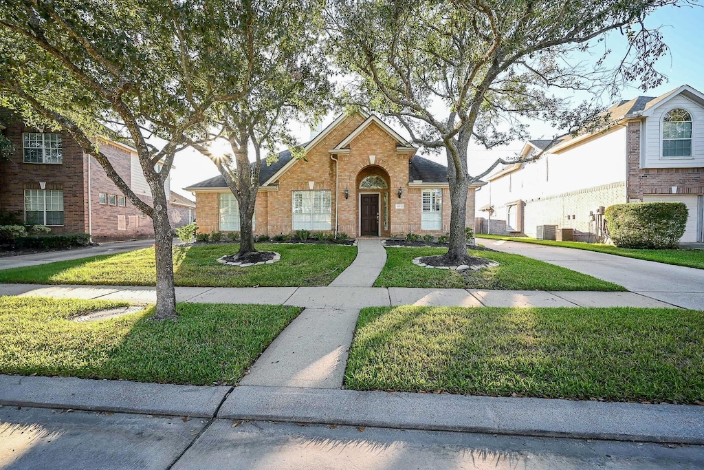 view of front of home with central AC unit and a front yard