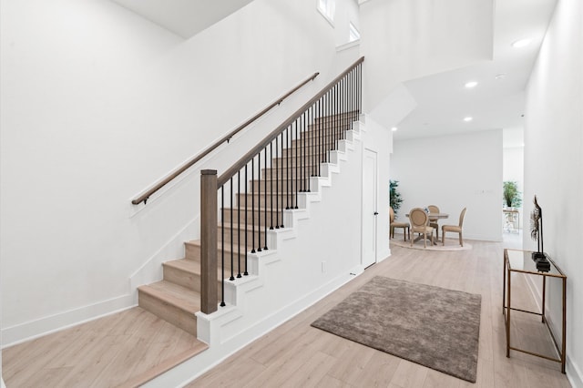 stairs featuring hardwood / wood-style floors and a high ceiling