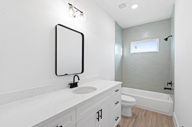 full bathroom featuring wood-type flooring, vanity, toilet, and tiled shower / bath combo