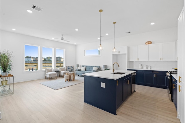 kitchen with ceiling fan, sink, stainless steel appliances, an island with sink, and white cabinets