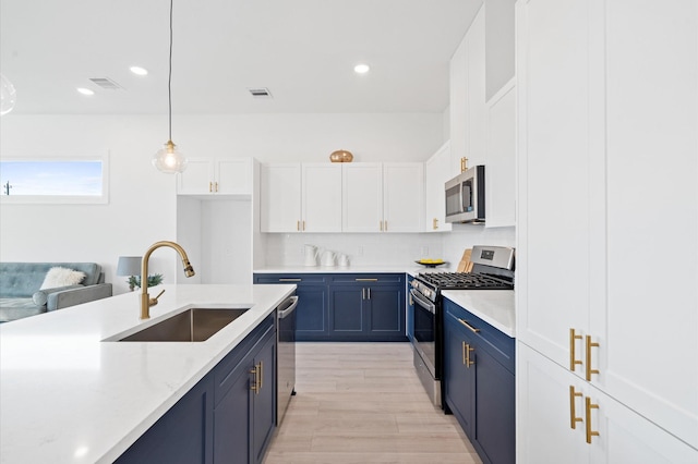 kitchen featuring white cabinets, blue cabinets, stainless steel appliances, and hanging light fixtures