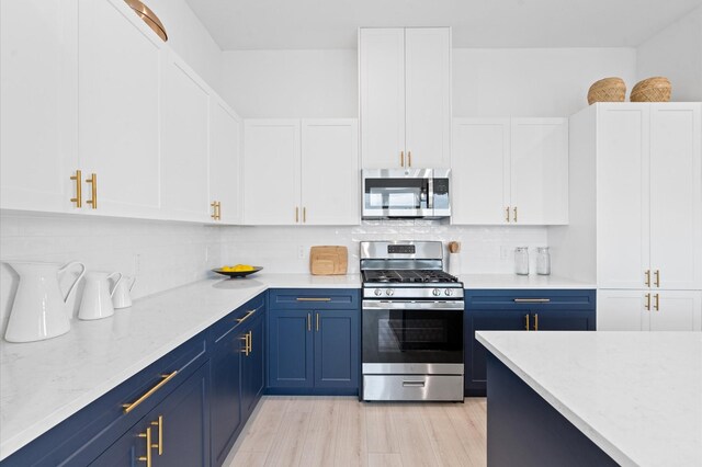 kitchen with blue cabinetry, white cabinetry, light stone countertops, stainless steel appliances, and decorative backsplash