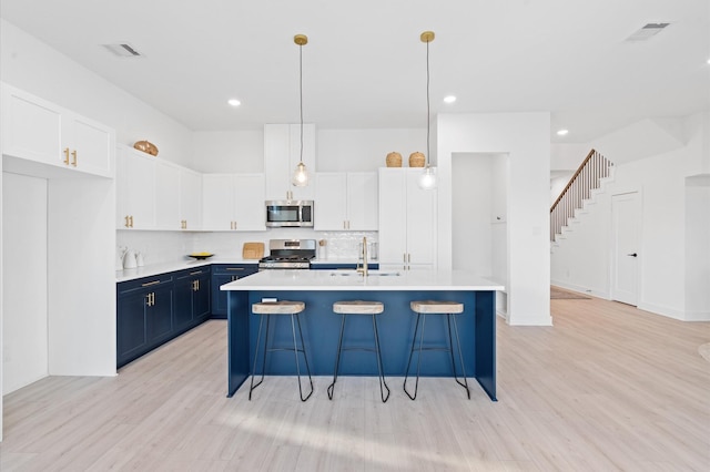 kitchen with blue cabinetry, appliances with stainless steel finishes, white cabinetry, and hanging light fixtures