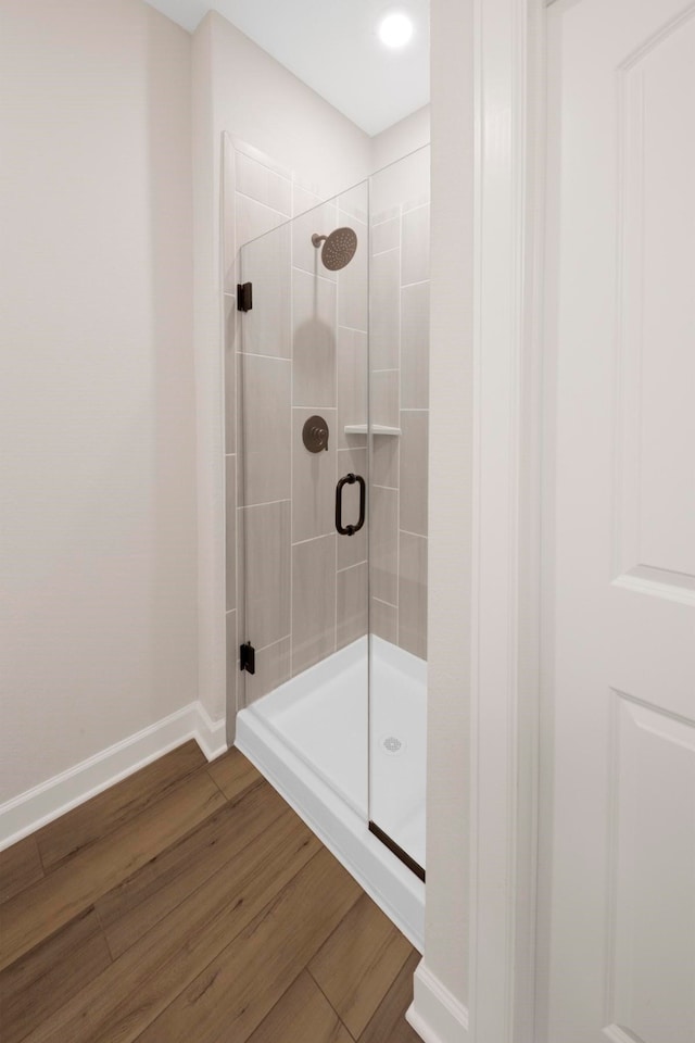 bathroom with wood-type flooring and a shower with door