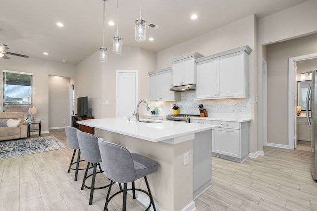 kitchen with white cabinets, decorative light fixtures, a center island with sink, and sink