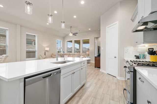 kitchen featuring pendant lighting, a center island with sink, white cabinets, sink, and stainless steel appliances