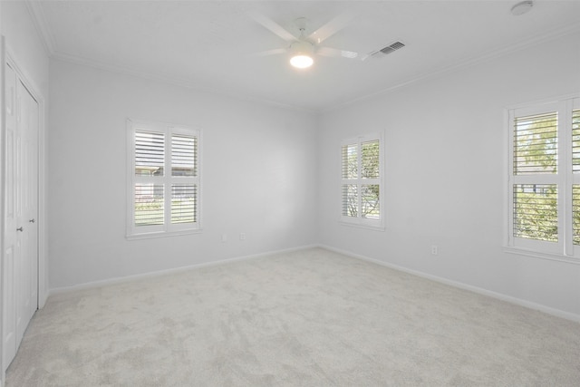 carpeted empty room featuring ceiling fan, crown molding, and a wealth of natural light