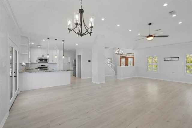 unfurnished living room featuring lofted ceiling, crown molding, sink, and ceiling fan with notable chandelier