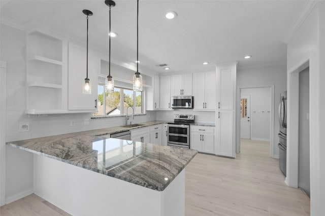 kitchen with kitchen peninsula, appliances with stainless steel finishes, white cabinetry, and sink