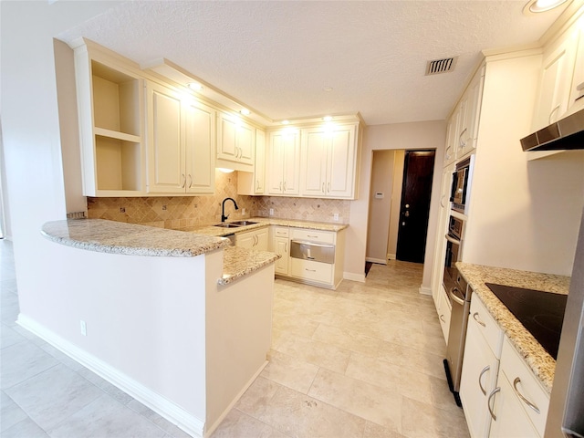 kitchen featuring kitchen peninsula, light stone countertops, sink, and black electric cooktop