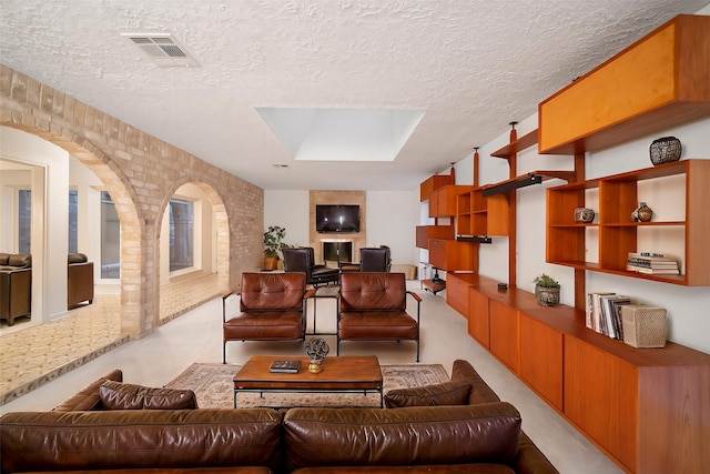 living room featuring a textured ceiling, a skylight, and brick wall