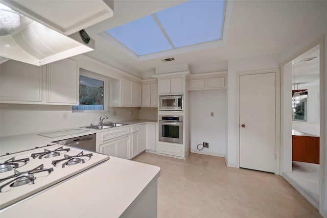 kitchen with appliances with stainless steel finishes, white cabinetry, exhaust hood, and sink