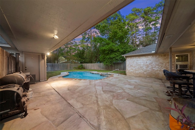 pool at dusk with cooling unit and a patio