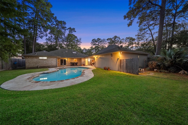 pool at dusk with a patio area and a yard