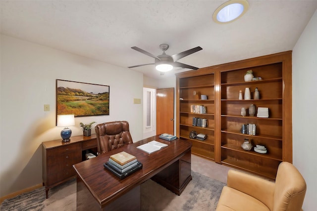 office with light carpet, built in shelves, and ceiling fan