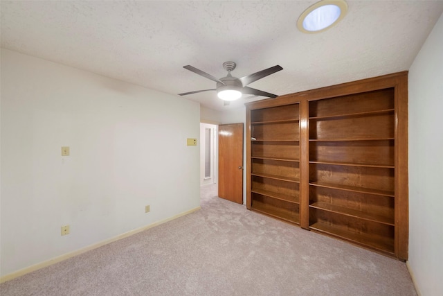 unfurnished bedroom with ceiling fan, light colored carpet, and a textured ceiling